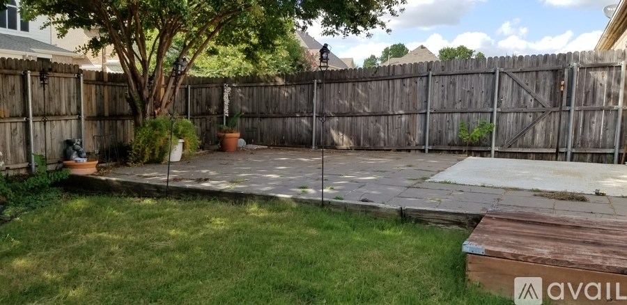 A backyard with a wooden fence and a tree.