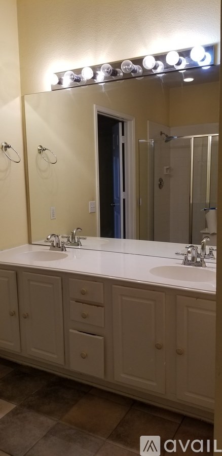 A bathroom with a vanity and a mirror with lights above it.