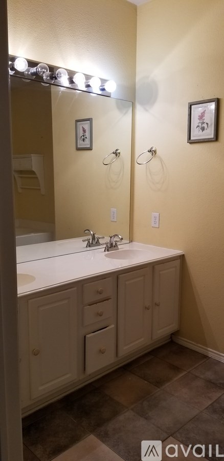 A bathroom with a white sink and brown tiles.