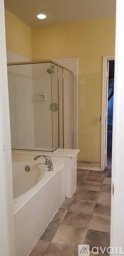 A bathroom with a white bathtub and a glass shower door.