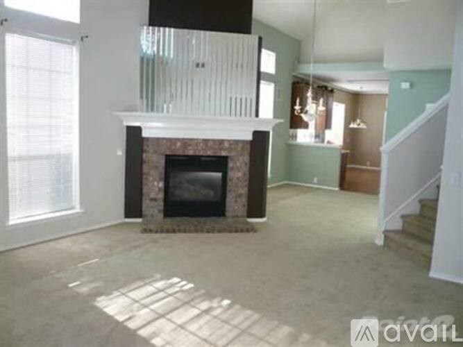 A living room with a fireplace and a staircase.
