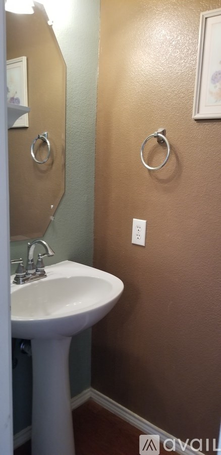 A bathroom with a white pedestal sink and brown walls.