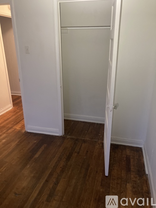 A white closet with a wooden floor.