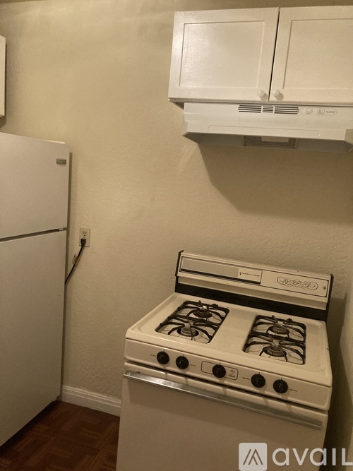 A white stove in a kitchen with a white fridge and white cabinets.