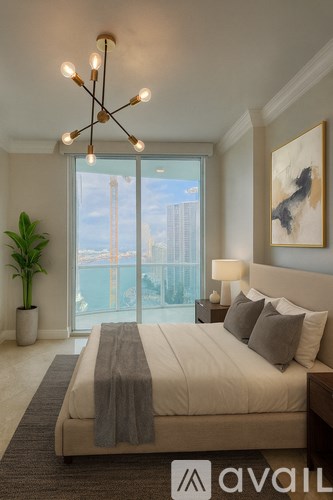 A bedroom with a large window overlooking a cityscape.