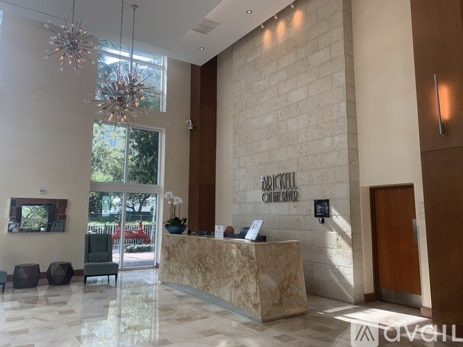 The reception area of a building with a marble counter and a chandelier hanging from the ceiling.