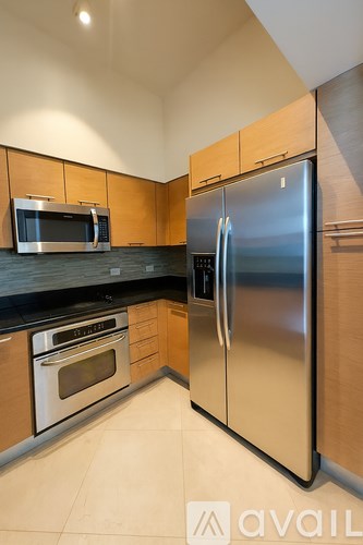 A kitchen with a stainless steel refrigerator and wooden cabinets.