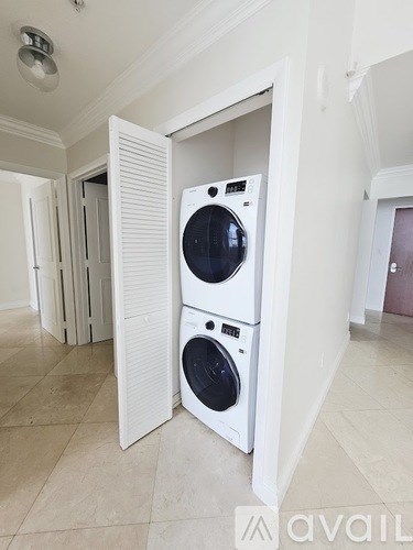 A washer and dryer are stacked on top of each other in a white cabinet.