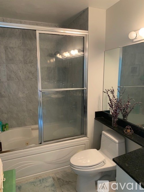 A bathroom with a toilet, a bathtub, and a glass shower door.