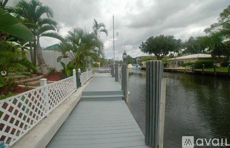 A wooden bridge over a body of water with a white fence on one side.
