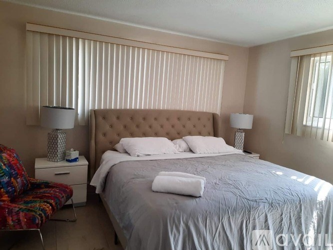 A bedroom with a large bed and a colorful chair.