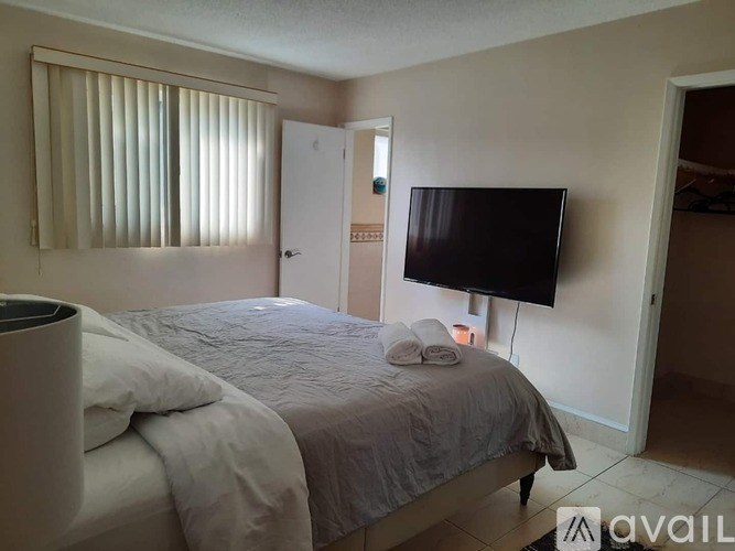 A bedroom with a bed, a television, and a trash can.