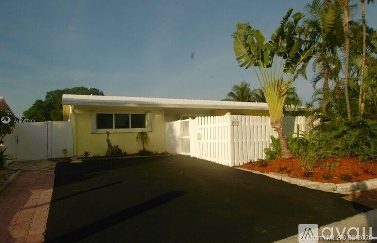 A house with a white fence and a driveway in front.