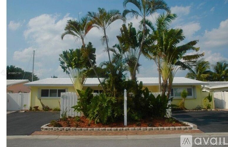 A house with a white fence and a yellow house in the background.
