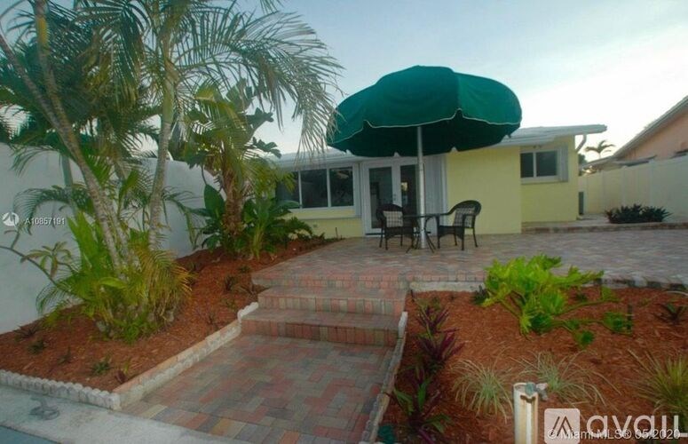 A patio with a green umbrella and a brick pathway.