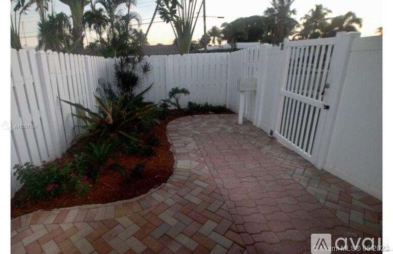A white fence with a brick pathway leading to it.