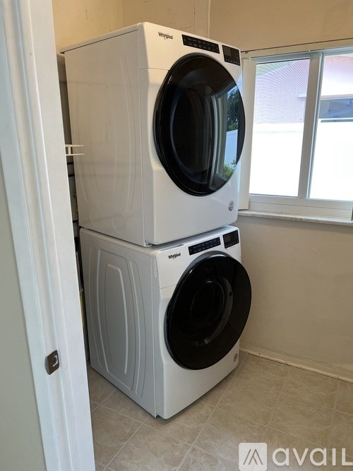 A stack of two white washing machines in a room.