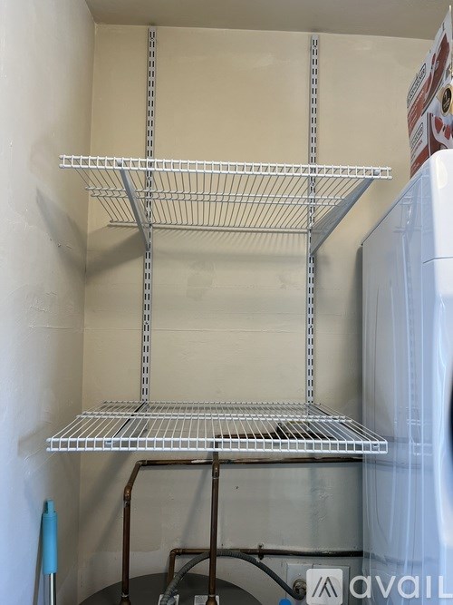 A metal shelving unit is in a room with a white wall.