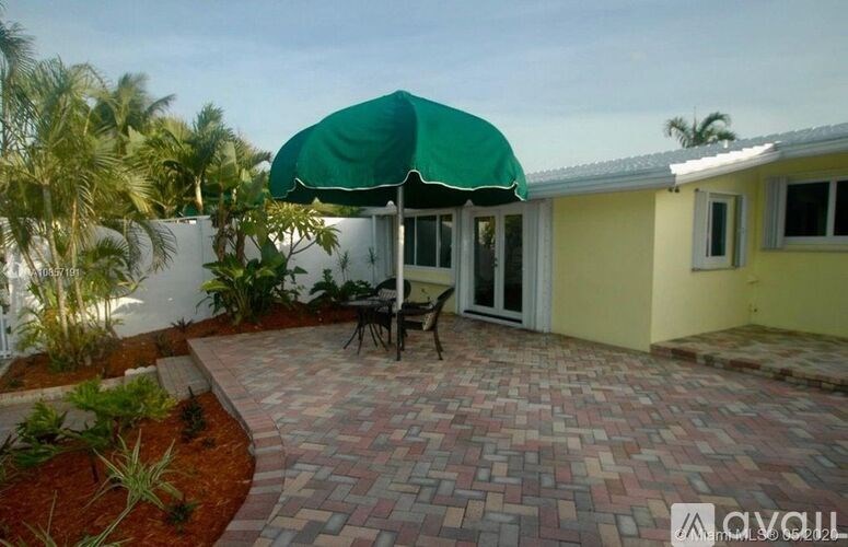 A patio with a table and chairs under a green umbrella.