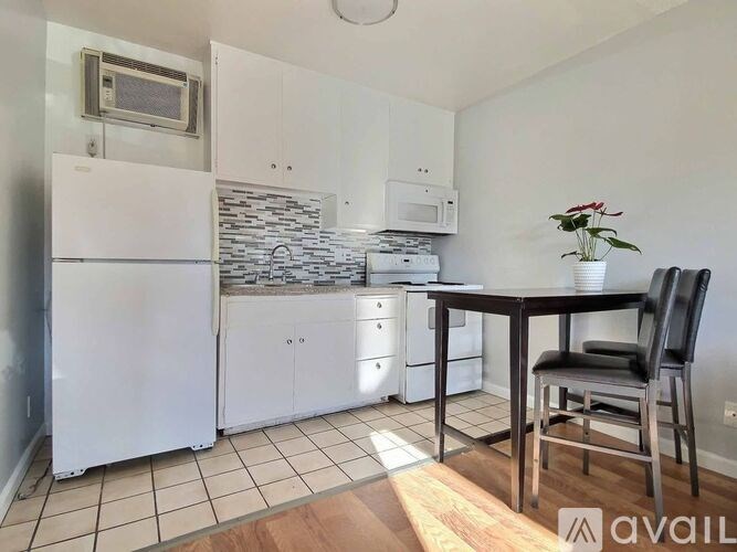 A kitchen with white appliances and a wooden table with a plant on it.