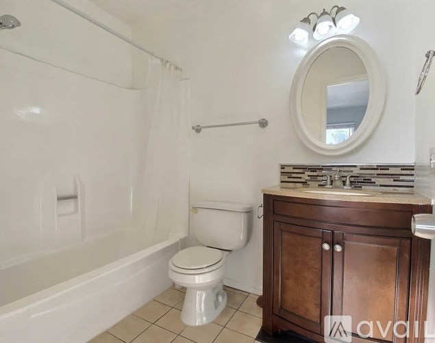 A white toilet sits in a bathroom next to a white bathtub.