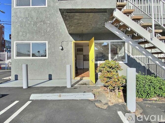 A modern building with a yellow door and a staircase leading to the upper floor.