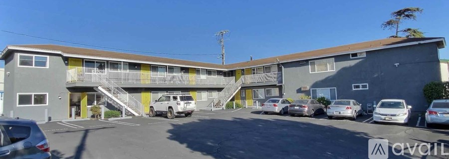 A parking lot with cars and a building with a balcony.