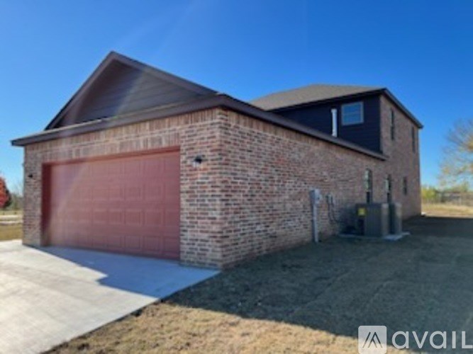 A brick house with a red garage door is for sale.