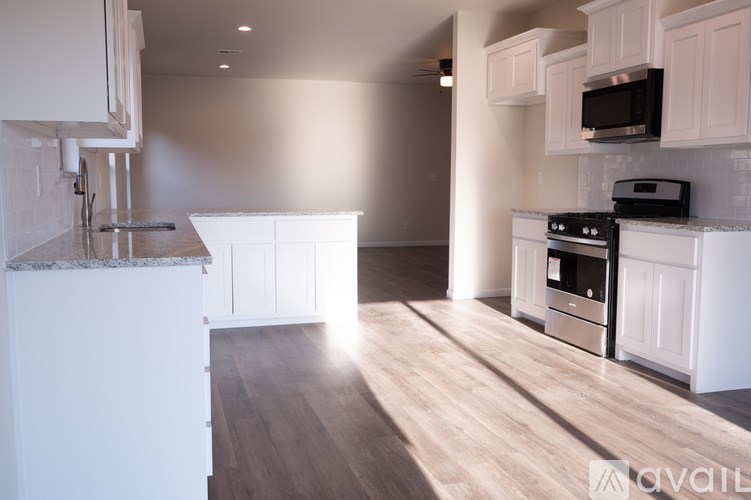 A kitchen with white cabinets and a wooden floor.