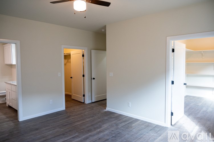 A room with a ceiling fan and a doorway leading to another room.
