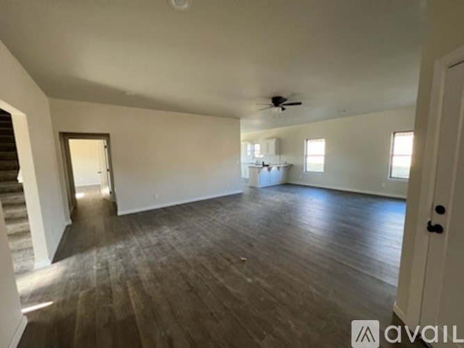 A spacious room with wooden floors and a ceiling fan.
