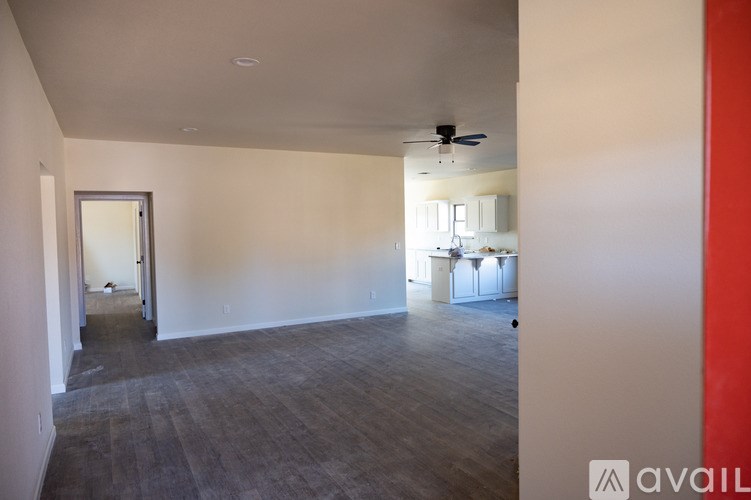 A spacious room with a ceiling fan and a doorway leading to another room.
