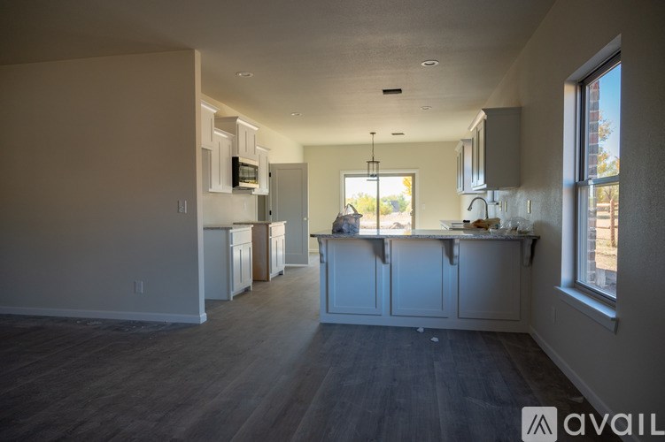 A kitchen with white cabinets and a wooden floor.
