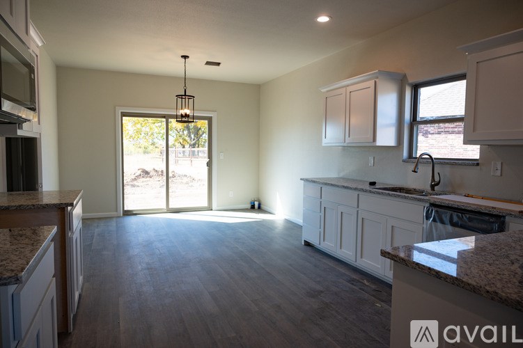 A kitchen with a granite countertop and white cabinets is available for rent.