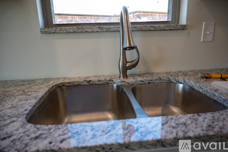 A kitchen sink with a chrome faucet and a granite countertop.