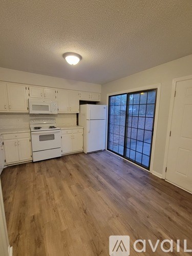 A kitchen with white cabinets and a wooden floor.