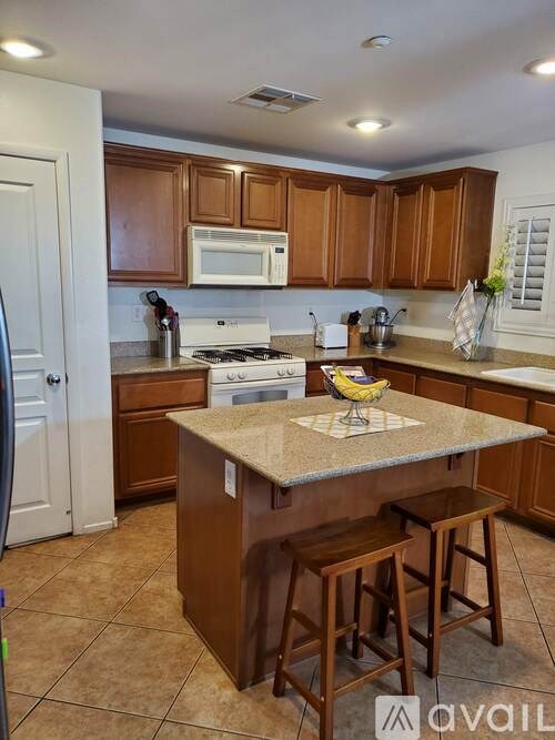 A kitchen with brown cabinets and a granite countertop.
