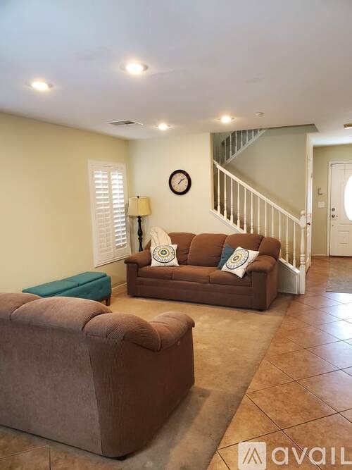 A living room with a brown couch and a green ottoman.