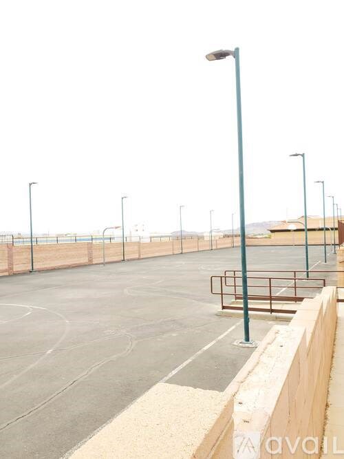 A basketball court with a fence and a basketball hoop.