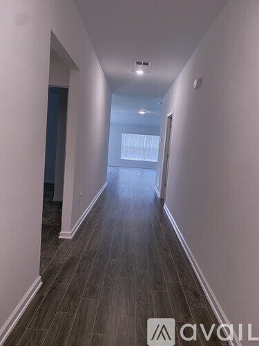 A long hallway with wood floors and white walls.