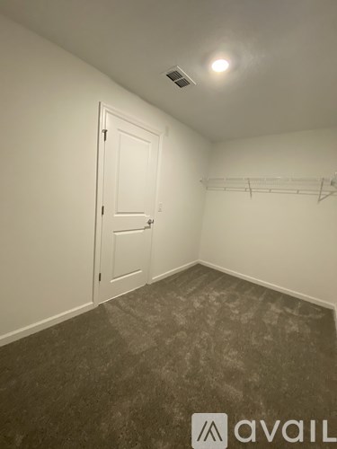 A room with a door and a shelf on the wall.