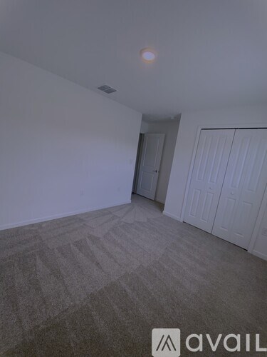 A room with a carpeted floor and a door in the background.