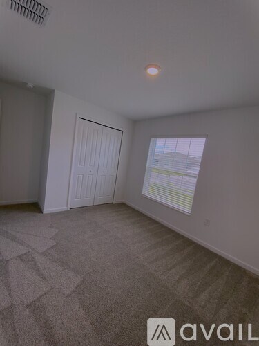 A room with a carpeted floor and a window with blinds.