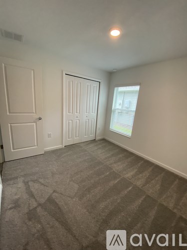 A room with a carpeted floor and a window with blinds.
