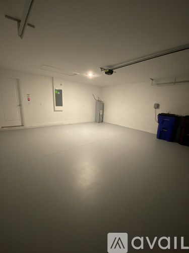 A large empty room with a white wall and a door on the left side.