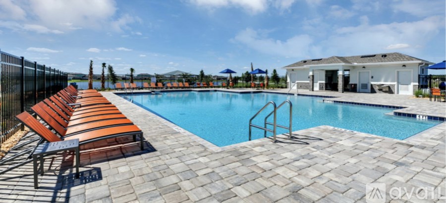 A pool with a black fence and red chairs.