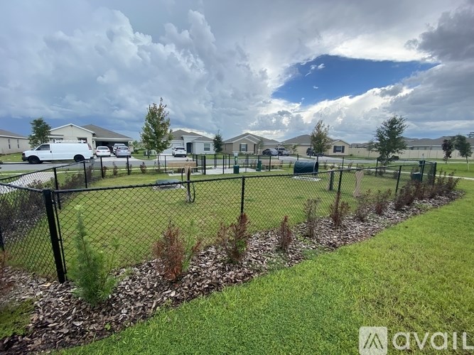 A fenced area with a grassy field and some trees.