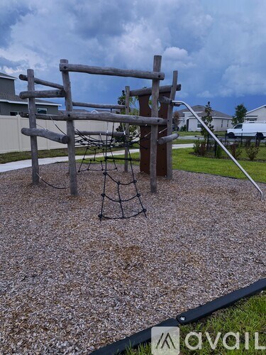 A playground with a wooden swing set and a rope swing.