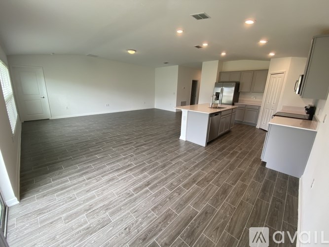 A spacious kitchen and dining area with wooden flooring and white cabinetry.