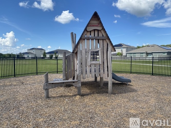 A wooden playground structure with a slide in the middle of a gravel area.